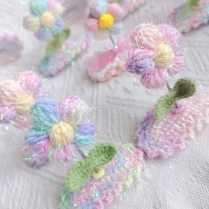 Detail of handmade crochet puff flower hair clips with pastel yarn and glitter accents