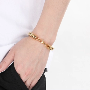 Close-up of a gold Byzantine chain bracelet with a lobster clasp worn on a male wrist