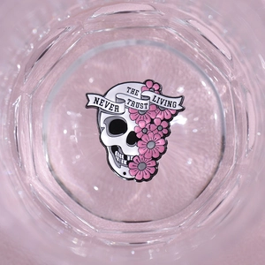 Macro shot of skull and pink floral enamel pin with Never Trust The Living text