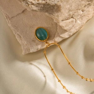Detail of 18K gold-plated stainless steel necklace with blue cat-eye stone on silk