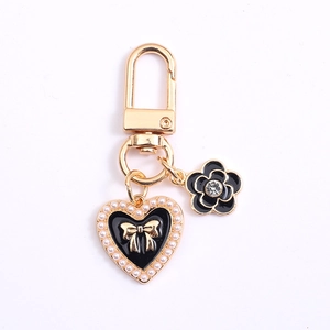 Elegant gold keychain with black enamel heart, pearl bow and crystal flower pendant