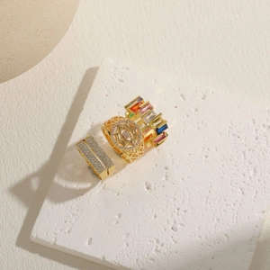 Three 14K gold plated geometric rings with crystals on a stone tray, top view luxury design