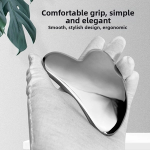 Close-up of ergonomic heart-shaped stainless steel Gua Sha tool for facial lifting