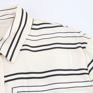 Close-up of cream satin shirt showing black striped pattern and lapel collar stitching