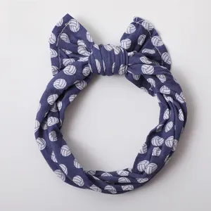 Detail of baby headband with white volleyball print and a soft navy blue bow knot