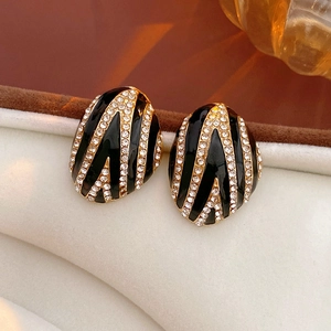 Macro detail of oval vintage earrings with black enamel, gold stripes and rhinestones