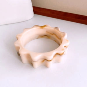 Gros plan d'un large bracelet en acrylique avec bord festonné et texture marbrée