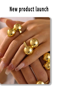 Detail of model wearing multiple gold chunky sphere rings with a high-polished metallic finish