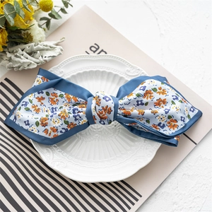 Close-up of blue floral satin bow hair clip on a decorative plate with chic backdrop