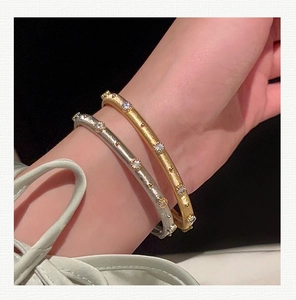 Macro shot of gold and silver brushed metal bracelets with shimmering micro-set zircons