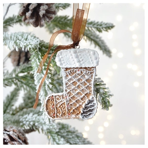Detailed view of gingerbread Christmas stocking ornament hanging on a snowy tree branch