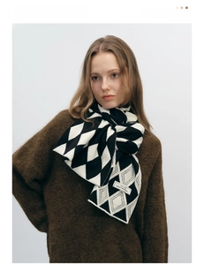 Close-up of black and white checkered knit scarf showing thick woolly texture and weave