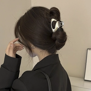 Silver streamlined metal shark clip shown from side-rear view on model's hair