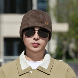 Detail of dark brown knit beanie with vertical ribbing and brown leather logo patch