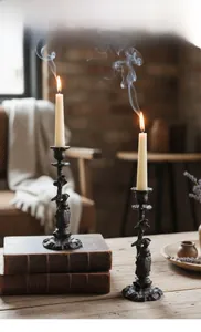 Detail of vintage cast iron candle holders with carved figures on decorative books