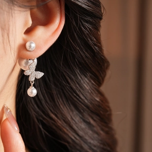 Detail of vintage gold plated butterfly earrings with pearls and zircons on model