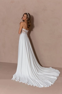 Detail of elegant lace embroidery and long trailing hem on a white slim-fit bridal gown