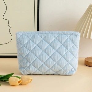 Detail of light blue quilted corduroy makeup bag with metal zipper in a cozy setting