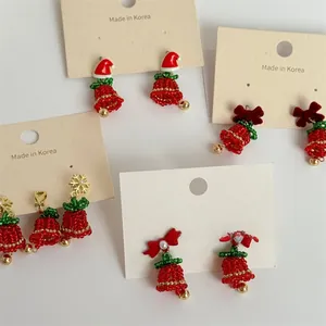 Macro detail of handmade beaded Christmas tree earrings with red velvet bows and pearls