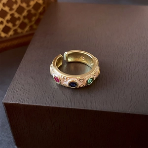 Detail of vintage gold ring with white enamel, heart patterns and colorful gems
