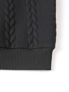 Detailed close-up of cable knit patterns and ribbed cuffs on black winter sweater
