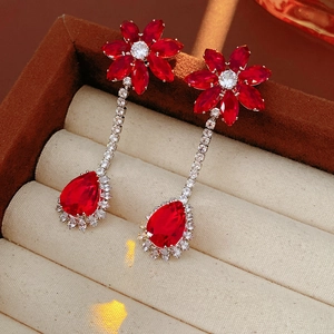 Detailed view of red drop pendant earrings with floral zircon accents in a velvet box