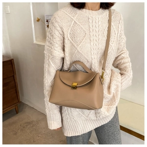 Detail of beige faux leather handbag featuring a golden square lock and adjustable strap