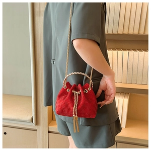 Detail of red rhinestone bucket bag with gold chain strap and metal tassel closure
