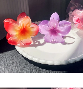 Detailed view of large floral resin hair claws in vibrant orange and soft purple colors