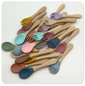 Flat lay of colorful baby silicone spoons and forks with ergonomic wooden handles