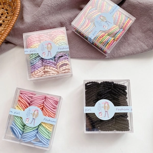 Detail view of colorful candy-colored elastic hair ties in transparent storage boxes