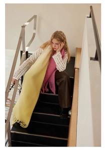 Detail view of pink and yellow gradient wool blend scarf with fringe worn by a model