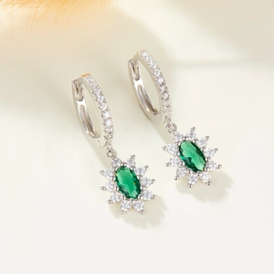 Detailed macro view of 925 silver hoop earrings with emerald green oval zircon stones