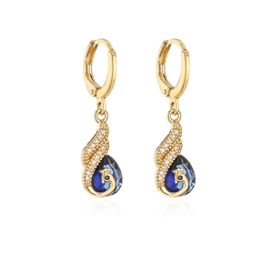 Macro shot of gold-plated peacock earrings with blue teardrop stones and zircons