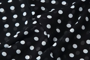 Close-up of black chiffon fabric with white polka dots showing soft texture and drape
