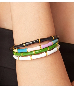 Detail of colorful bamboo style enamel bracelets with gold accents on female wrist