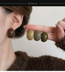 Gros plan de boucles d'oreilles en résine de couleur Morandi sur un mannequin en tons terre