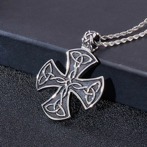 Macro detail of silver Celtic cross pendant with knot patterns and vintage rope chain