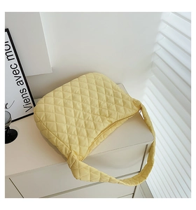 Detailed shot of yellow quilted puff shoulder bag on a white cabinet in natural light