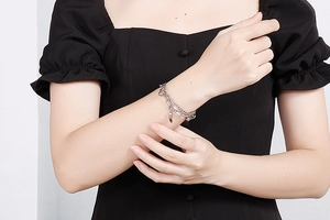 Close-up of a double-layered silver heart pendant bracelet on a model wearing black