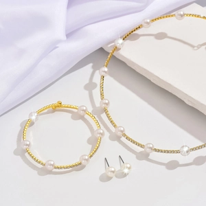 Detailed view of gold necklace, bracelet and stud earrings set with pearls and crystals