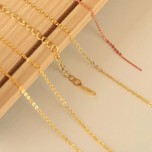 Macro view of 18K gold and rose gold necklace chains with extension links on wood