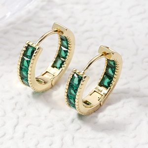 Elegant gold hoop earrings with green square-cut stones on a white textured background