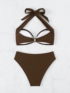 Detalle de top de bikini halter marrón oscuro con hebilla plateada sobre mármol