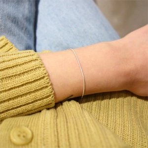 Minimalist S925 sterling silver slim chain bracelet worn over yellow knit sleeve