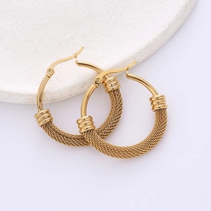 Golden titanium steel hoop earrings with woven texture on white stone tray