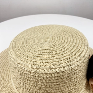 Close-up of the beige woven straw hat crown featuring intricate spiral texture and black ribbon