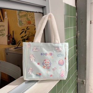 Detail einer süßen blauen Stofftasche mit Hasenmotiven und weichen weißen Plüschgriffen