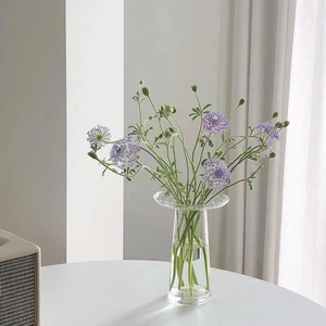 Close-up of a modern flying saucer-shaped glass vase neck on a white round table