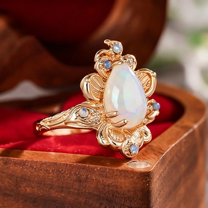 Elegante goudkleurige bladring met druppelvormige opaal en kleine blauwe edelstenen